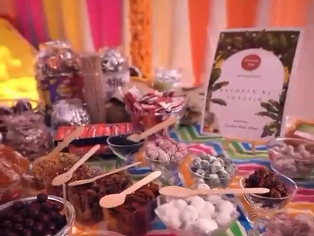 Bowls of retro Indian sweets with wooden scoops along the candy bar stall table, a Bachpan Ki Yaadein menu card standing behind them
